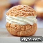 Close up on a choux bun filled with cream over a beige plate