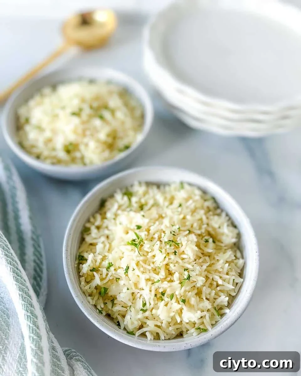 Instant Pot coconut rice in a bowl on a striped kitchen towel next to another Instant Pot side dish. Large serving spoon and stack of plates in background.