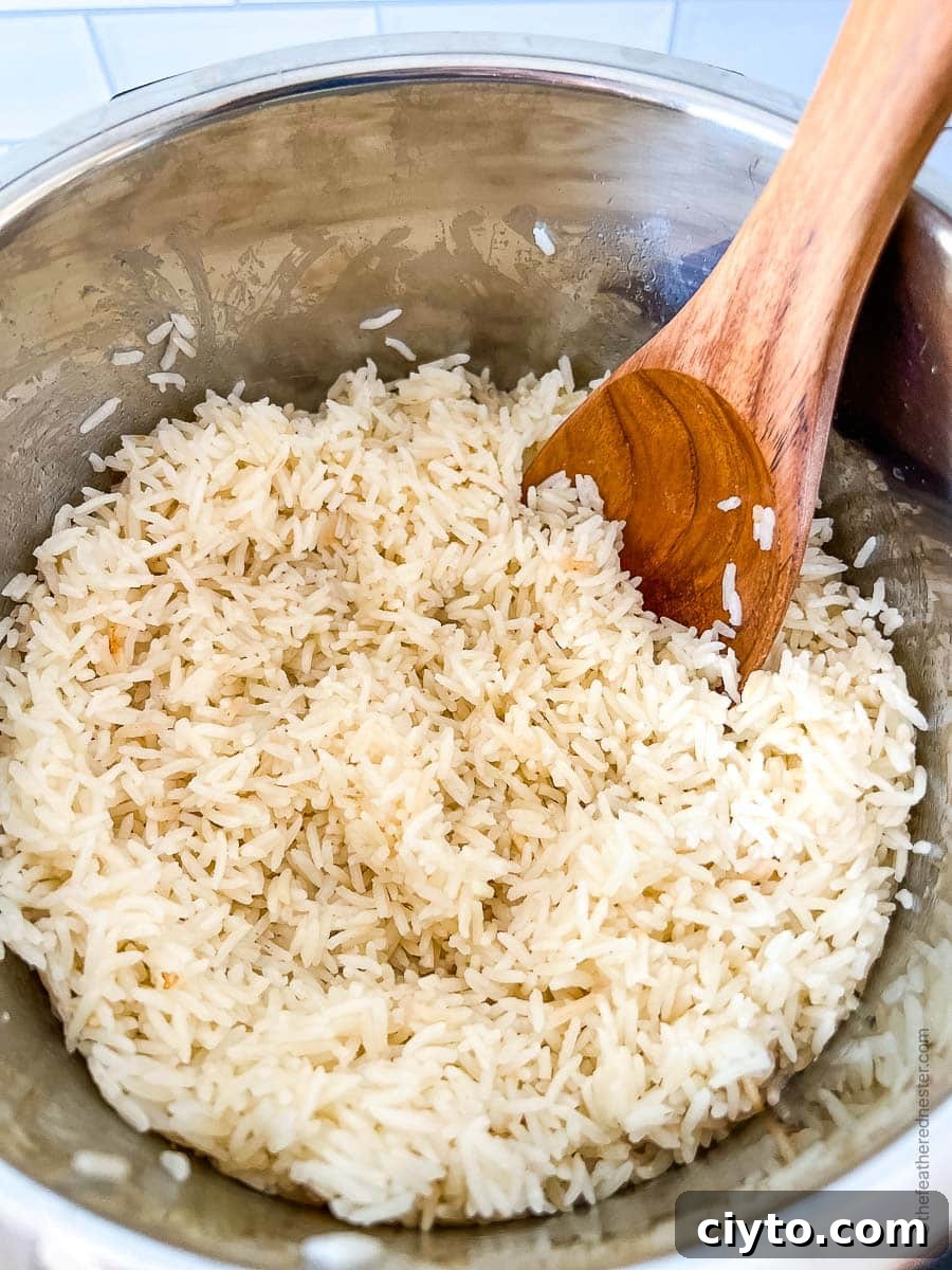 Fluffing the cooked coconut rice using a wooden spoon in the Instant Pot.