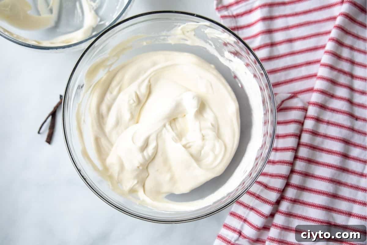 Large mixing bowl with whipped cream folded into sweetened condensed milk.