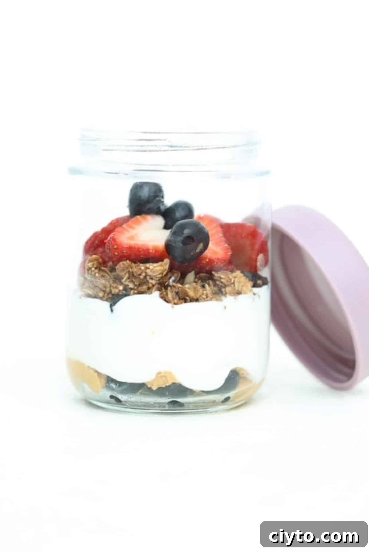 Yogurt parfait with a layers of peanut butter, Greek yogurt, granola and berries in a glass jar.