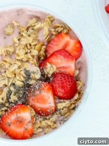 One strawberry smoothie bowl topped with granola, chia seeds, and sliced strawberries.