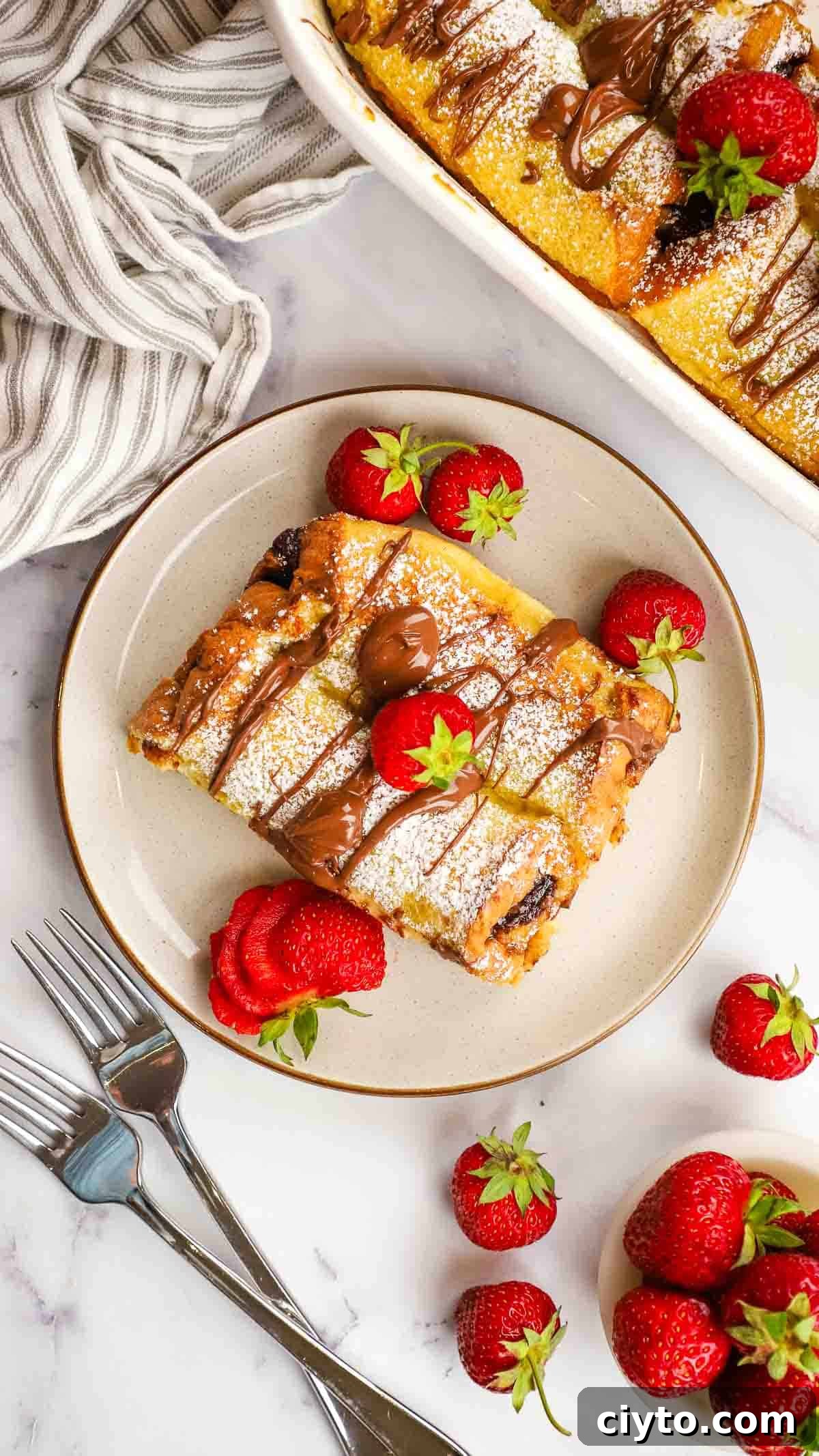 an overhead view of nutella french toast served on a plate with fresh strawberries on the side