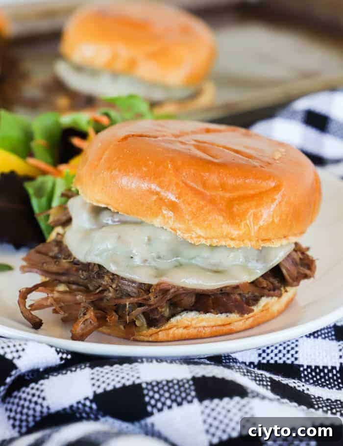 Slow Cooker Shredded Beef Sandwich Recipe 4 Slow Cooker Shredded Beef Sandwiches on a white plate with salad