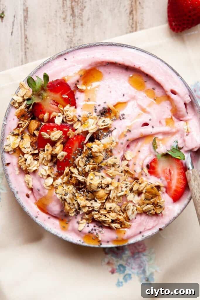 high protein strawberry smoothie bowl topped with granola, honey drizzle, chia seeds, and fresh strawberries