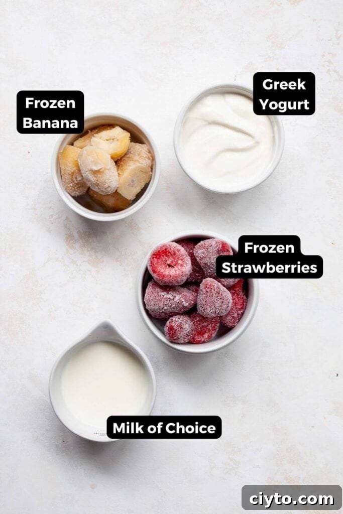 all ingredients in a strawberry smoothie bowl in small bowls with labels, including: greek yogurt, frozen banana, frozen strawberries, and milk