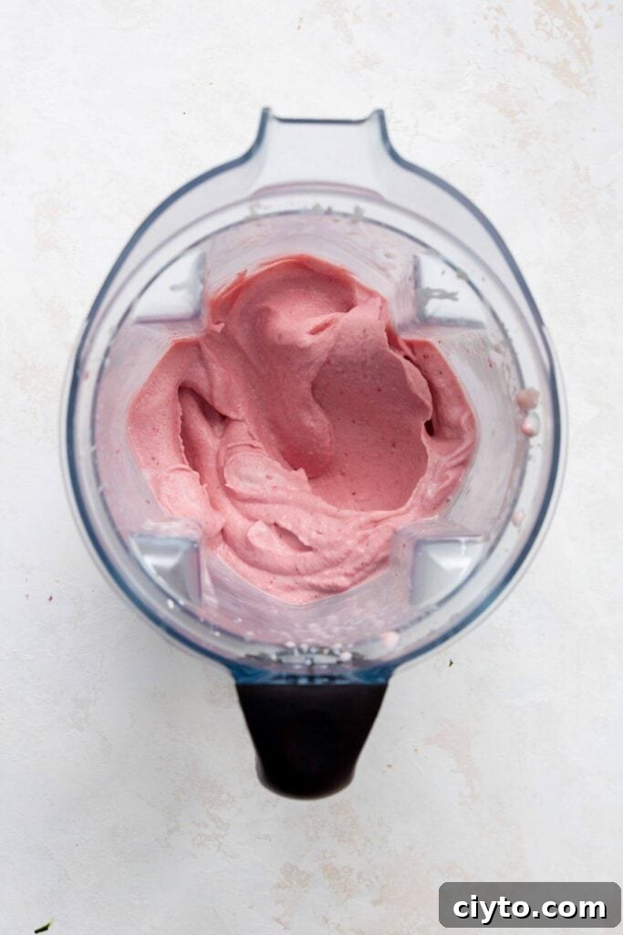 Thick and creamy strawberry smoothie blend inside a blender, ready to pour into a bowl