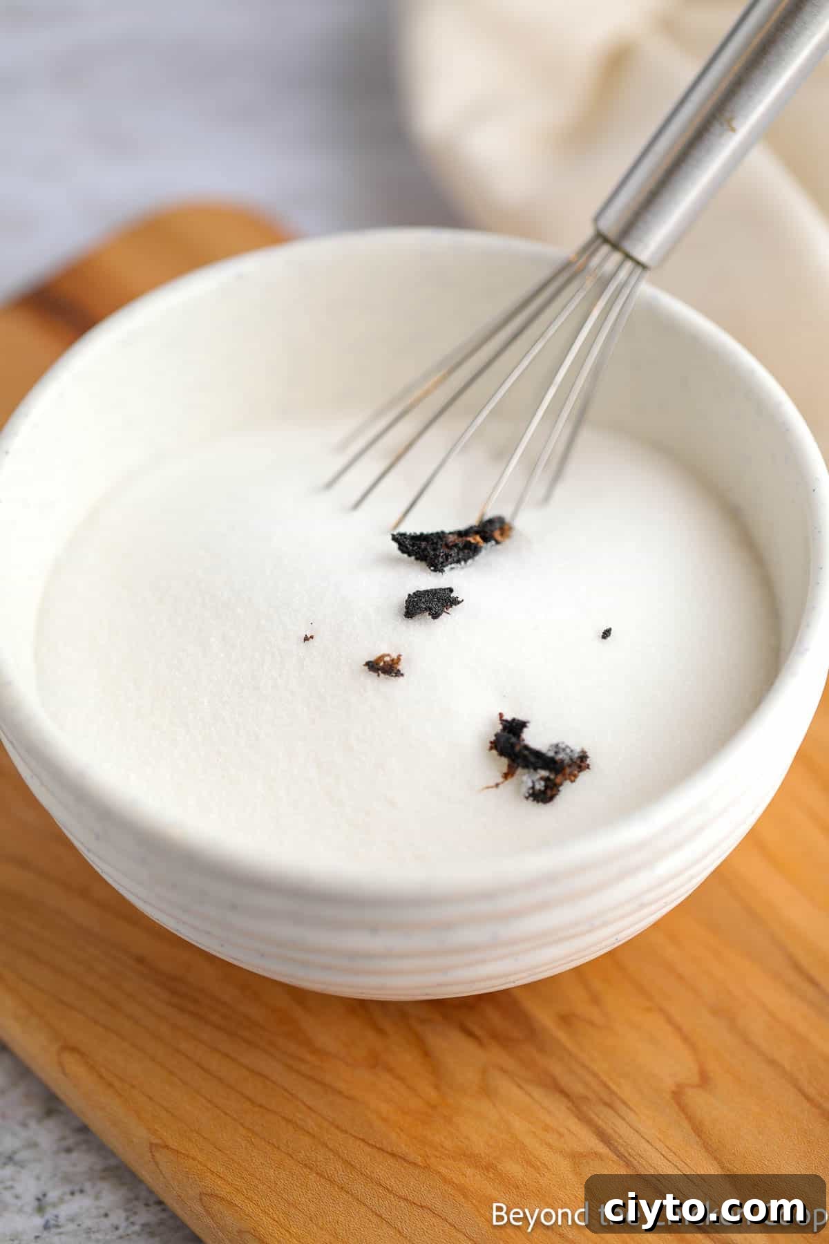 Vanilla in a bowl of sugar with a whisk.