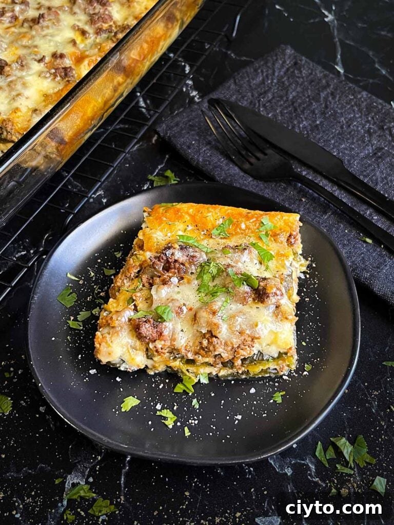 A serving of chile relleno casserole on a dark plate with the casserole in the background.