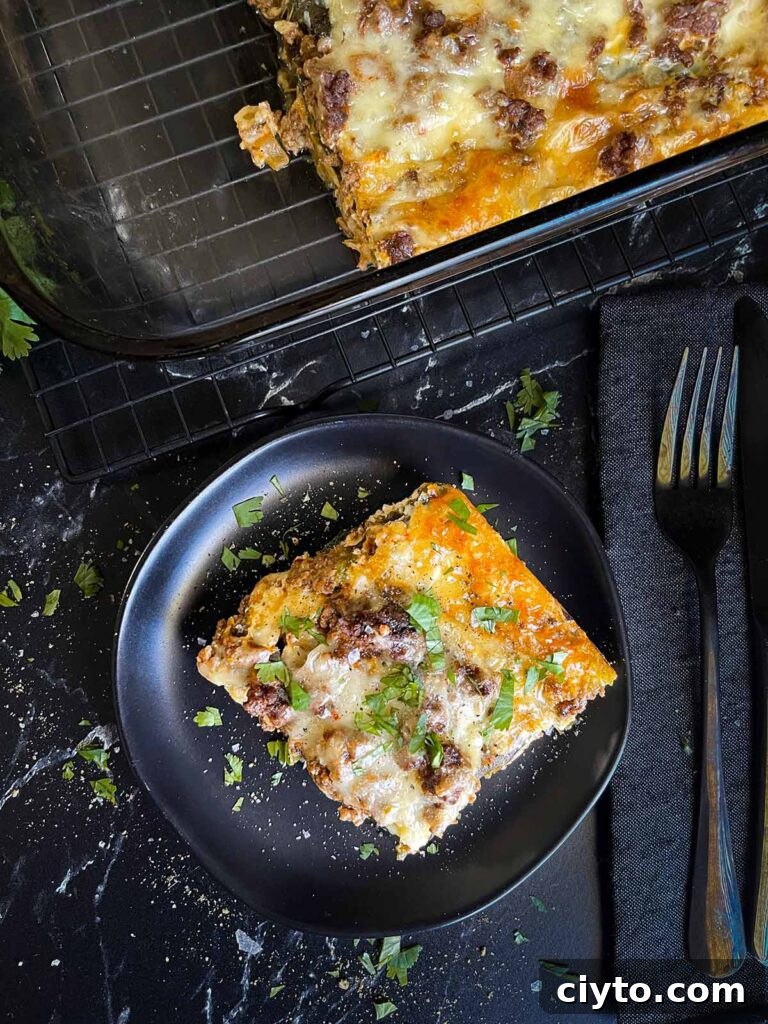 A serving of chile relleno casserole on a dark plate with the casserole in the background.