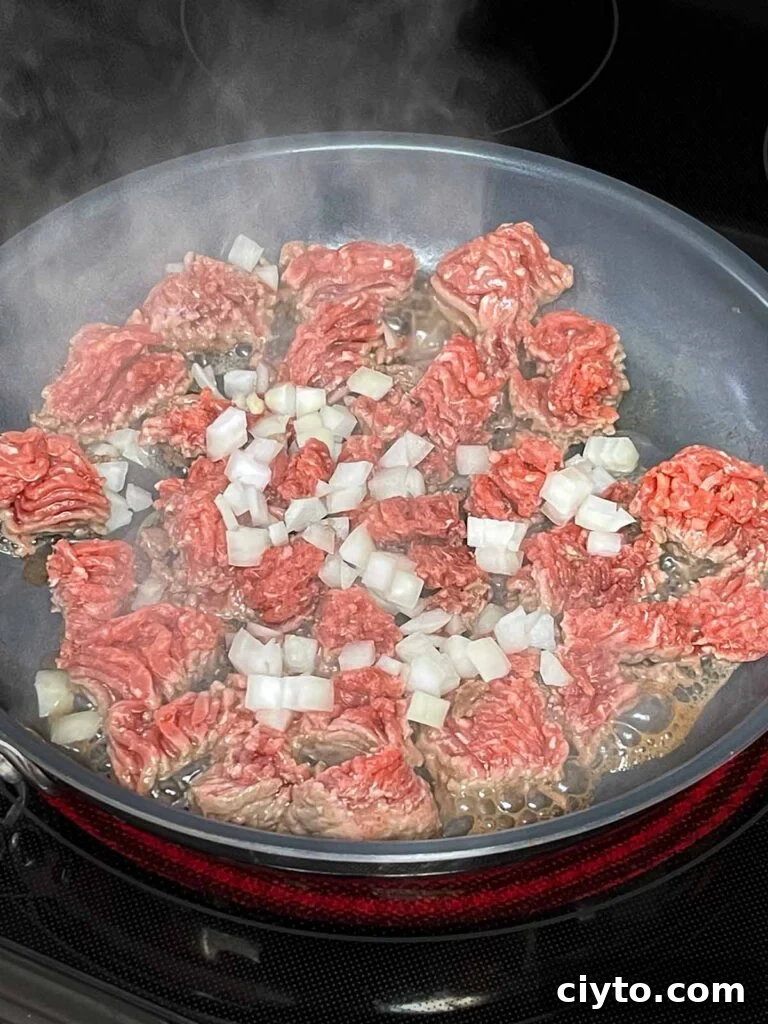 Ground beef with onions browning in a skillet.