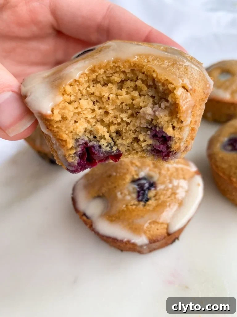 blueberry muffins with lemon coconut glaze, one with a bite taken out of it