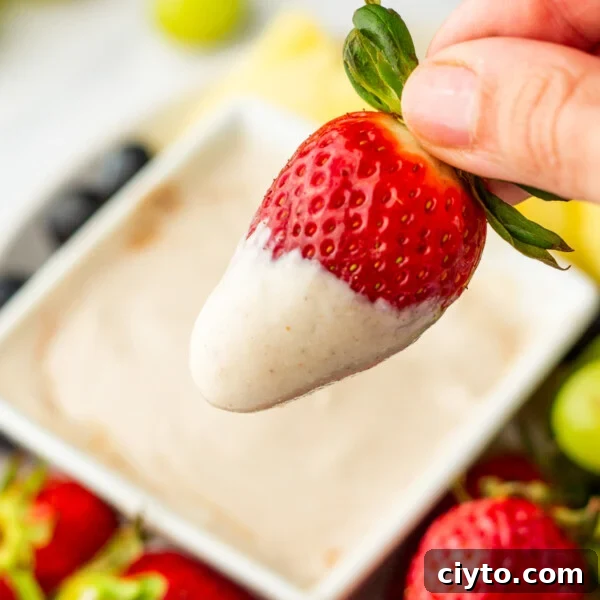 An overhead image of dipping a piece of strawberry to the fruit dip.