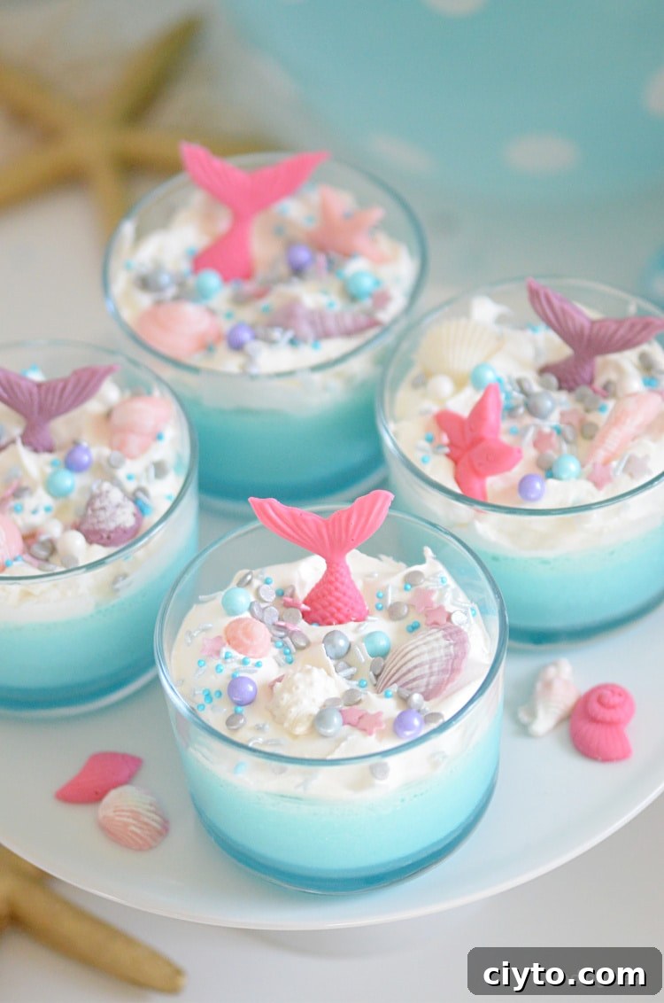 Mermaid Jello Cups are a simple but magical mermaid party idea that guests of all ages will love. Dive into jello mousse cups topped with whipped topping, fun sprinkles, chocolate mermaid tail and sea shells!