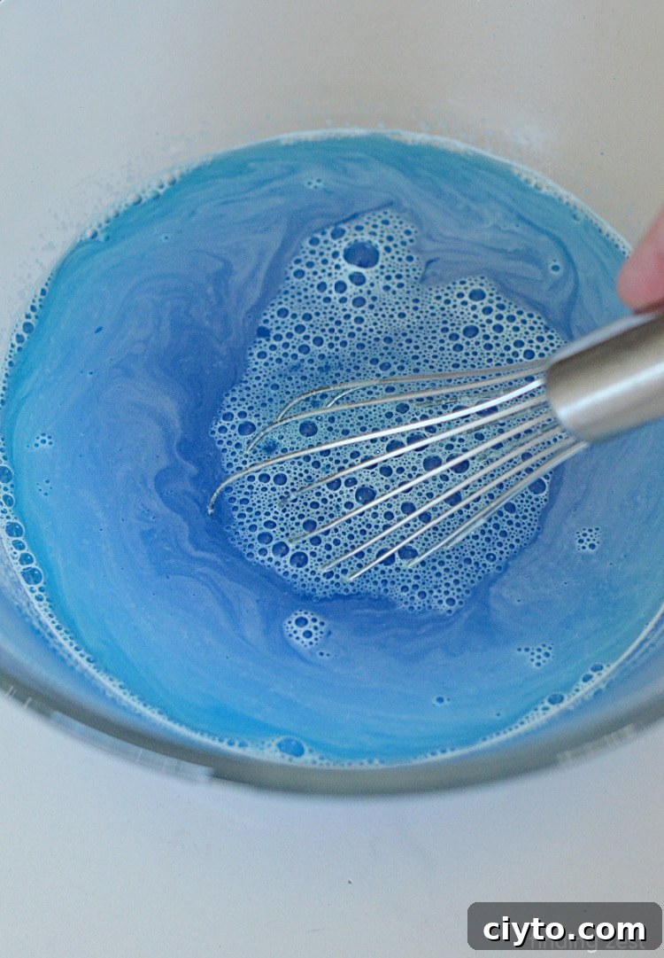 Using a whisk to stir berry blue Jello.