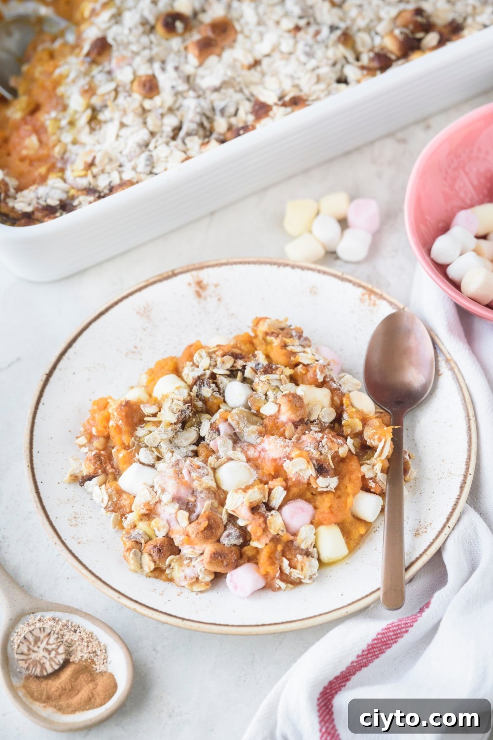 Copycat Boston Market Sweet Potato Casserole Recipe 3 A white plate full of sweet potato casserole on a white counter. A spoon rests on the plate.
