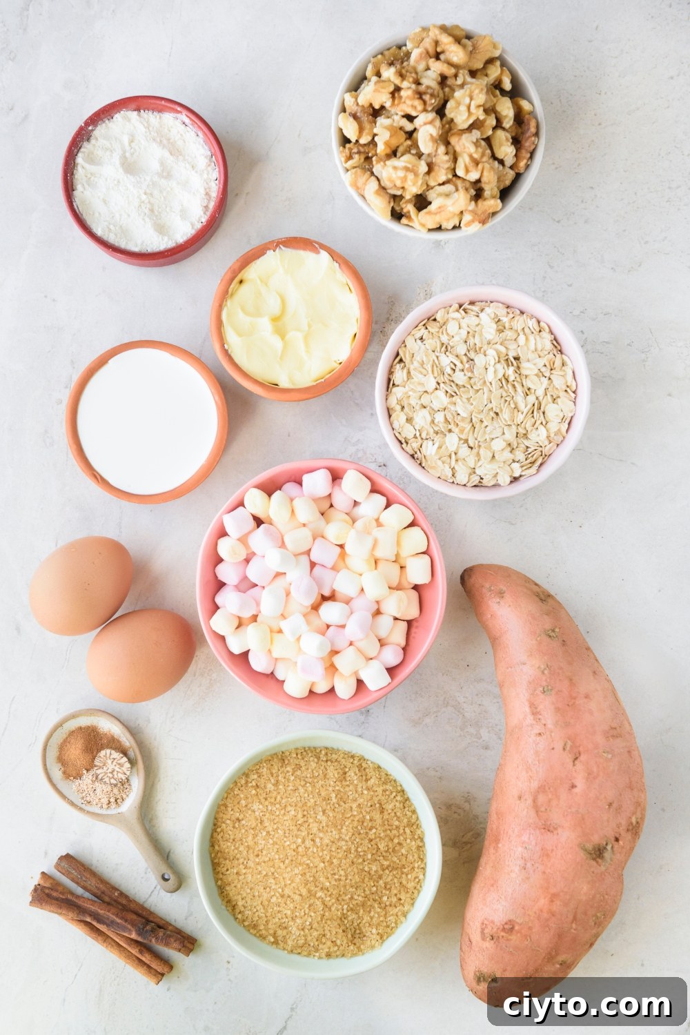 Copycat Boston Market Sweet Potato Casserole Recipe 4 Walnuts, flour, cream, oats, mini marshmallows, butter, and brown sugar are in separate bowls. A large sweet potato is next to them on a white counter.