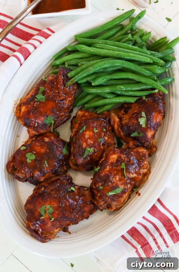 Six chicken thighs on an oval platter with a side of green beans.