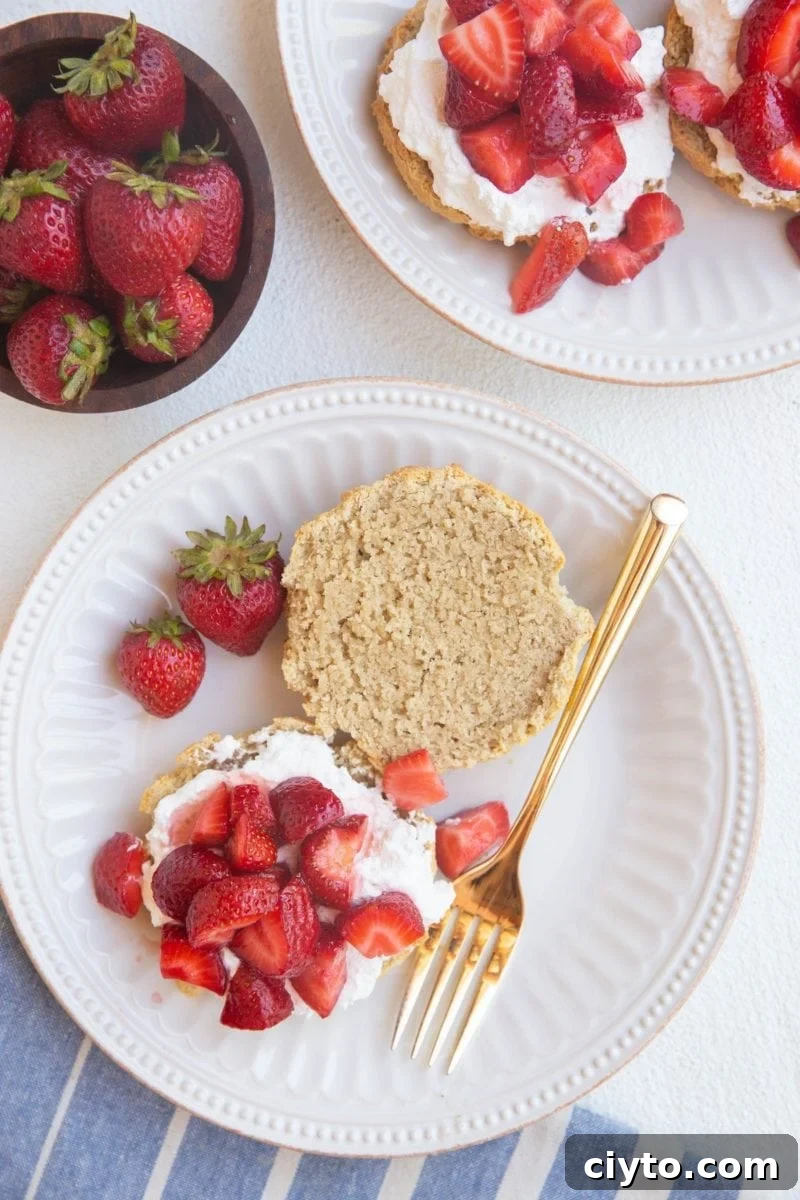 top down photo of strawberry shortcakes on two white plates with a blue striped napkin
