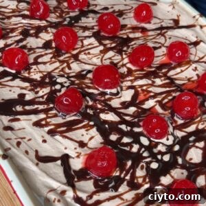 A dessert topped with whipped cream, drizzled with chocolate syrup, and decorated with maraschino cherries.