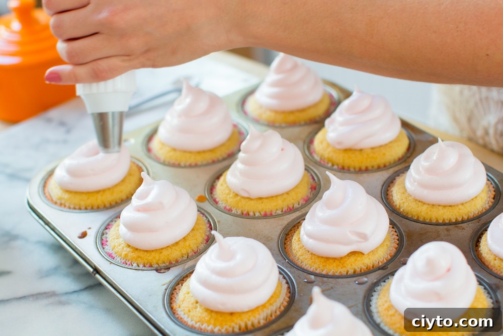 thick swirls of pink meringue are piped onto the top of the baked cupcakes