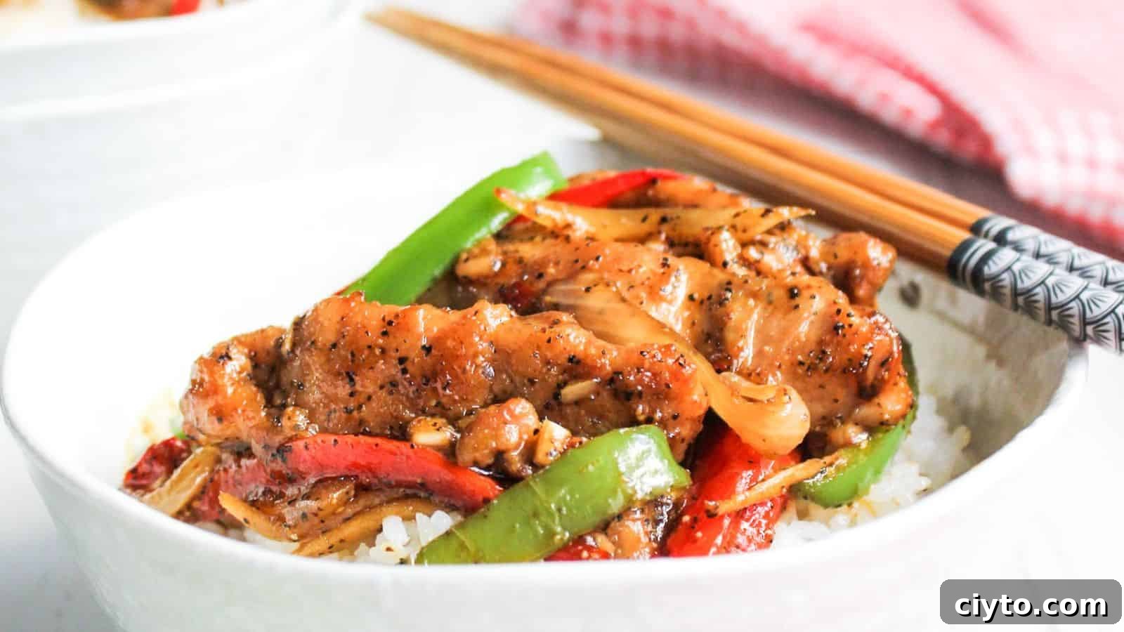 Bowl of black pepper chicken with chop sticks.
