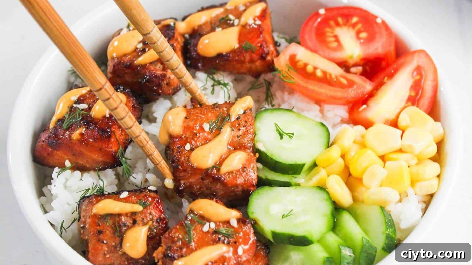 A bowl of white rice topped with glazed salmon, sliced cucumbers, corn, tomato wedges, and a drizzle of orange sauce, with chopsticks picking up a piece of salmon.