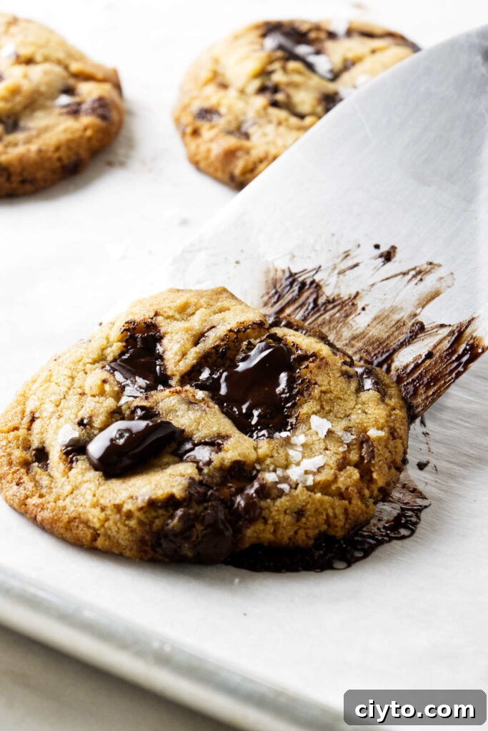 Egg Yolk Cookies Recipe: Crispy, Buttery Treats 9 Using a spatula to scoop a cookie off a baking sheet.