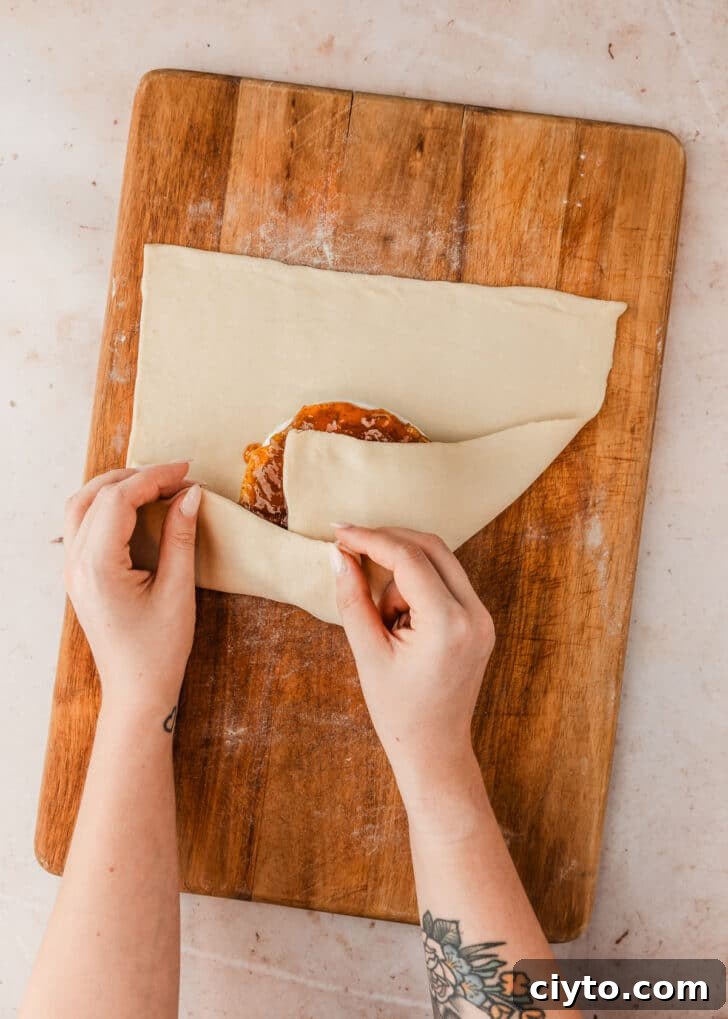 3-Ingredient Brie and Jam Puff Pastry Bites 7 Hands wrapping brie and jam in puff pastry.