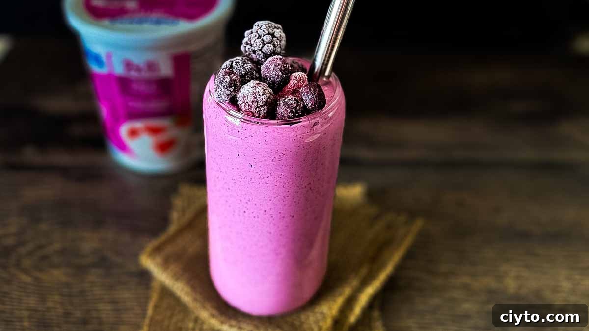 A tall glass of cottage cheese smoothie, garnished with frozen mixed berries.