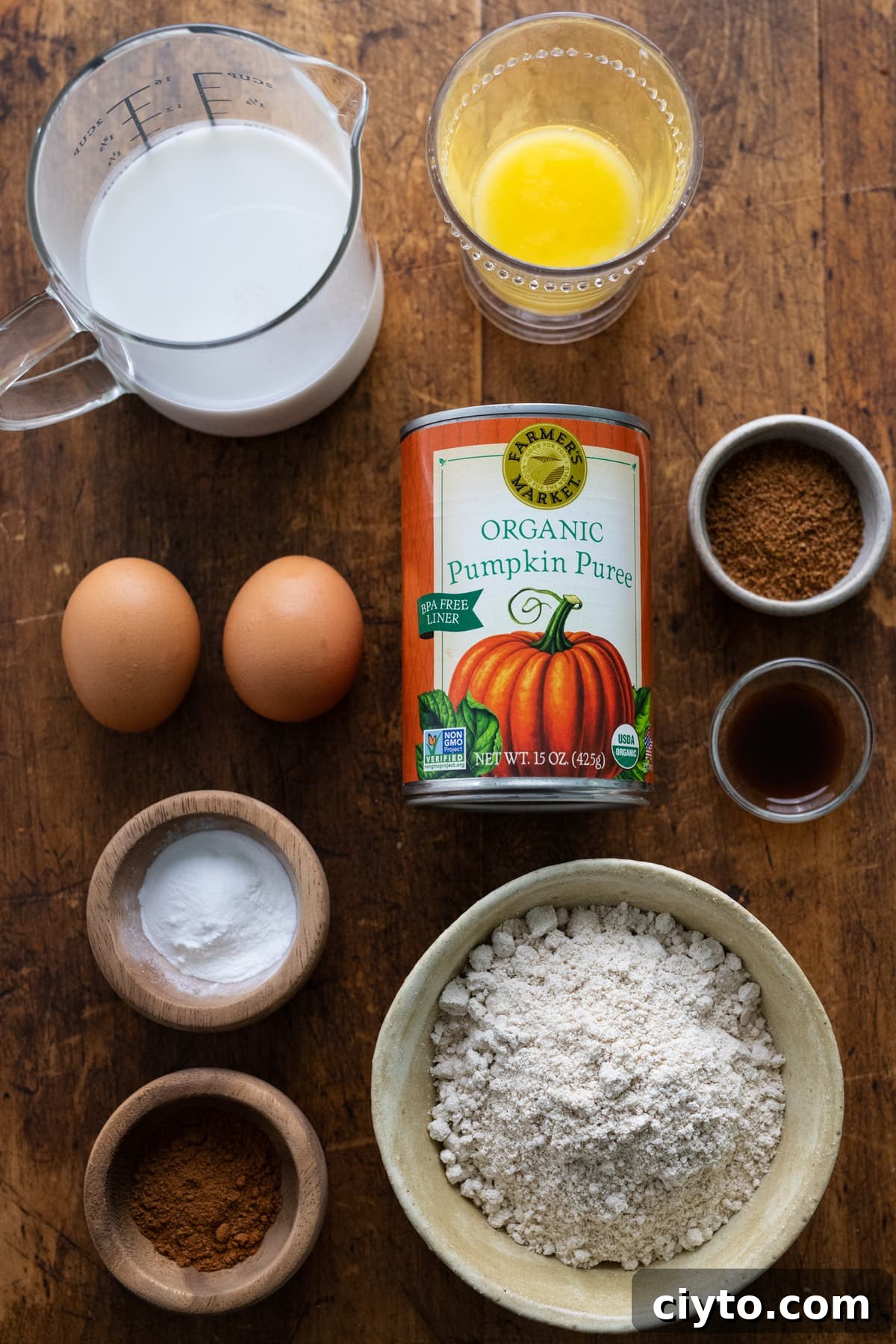 Ingredients for healthy pumpkin spice pancakes arranged on a wooden background.