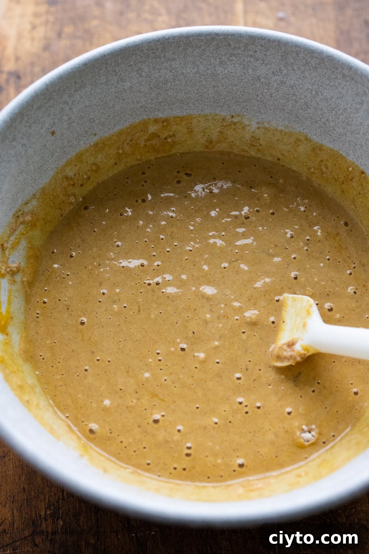 Pancake batter in a white bowl with a rubber spatula.