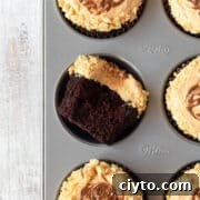 A chocolate cupcake in a muffin tin with peanut butter frosting.