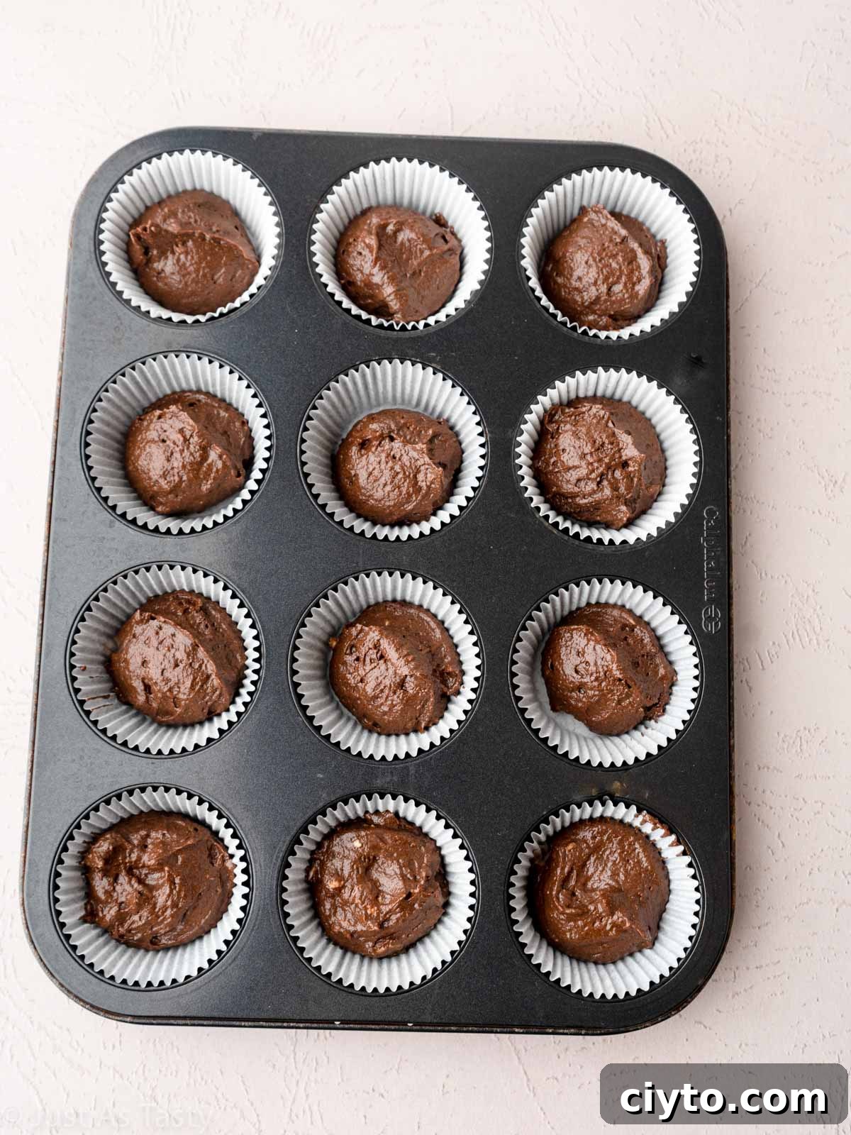Chocolate cupcake batter in muffin tin.