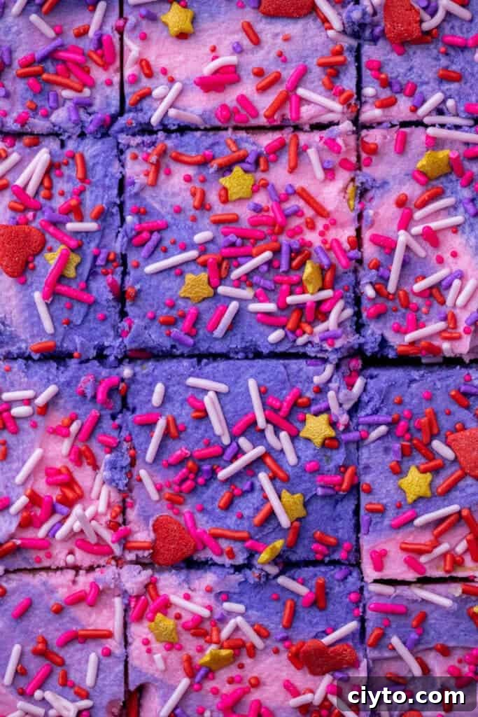 Valentine’s Day sugar cookie bars cut into squares and topped with pink and purple frosting and sprinkles