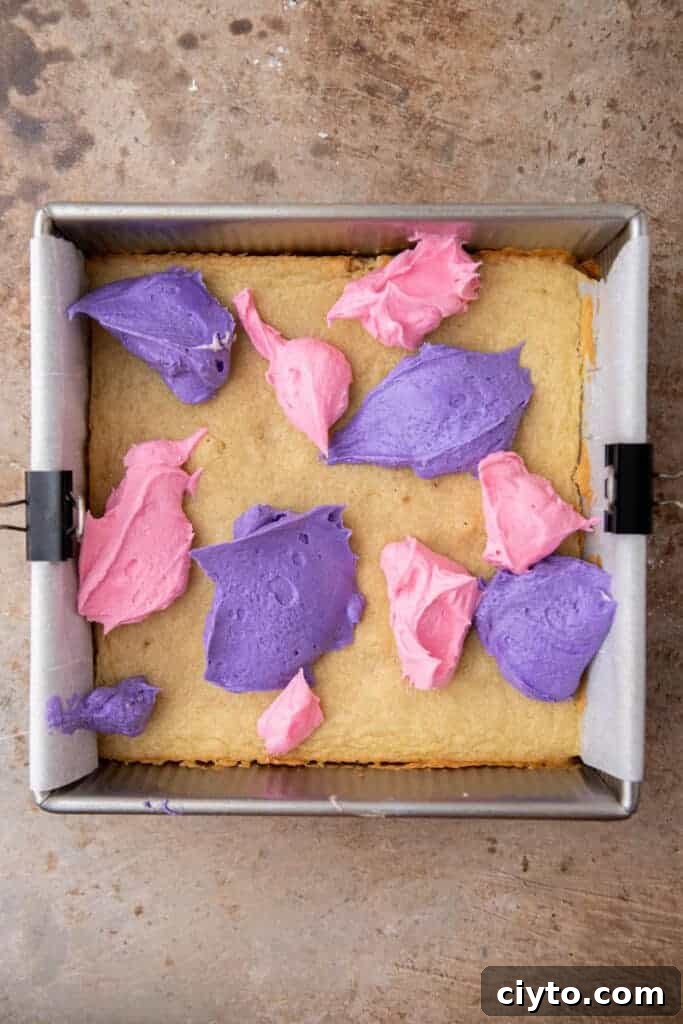 Pink and purple buttercream frosting dolloped onto baked cookie bars