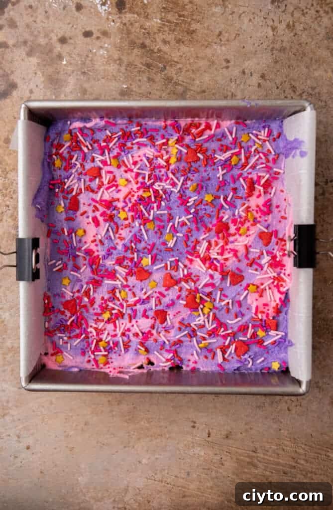 Valentine’s Day sugar cookie bars frosted with pink and purple buttercream and sprinkles