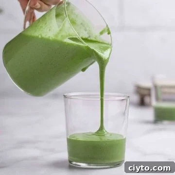 banana and spinach smoothies getting poured into a cup.