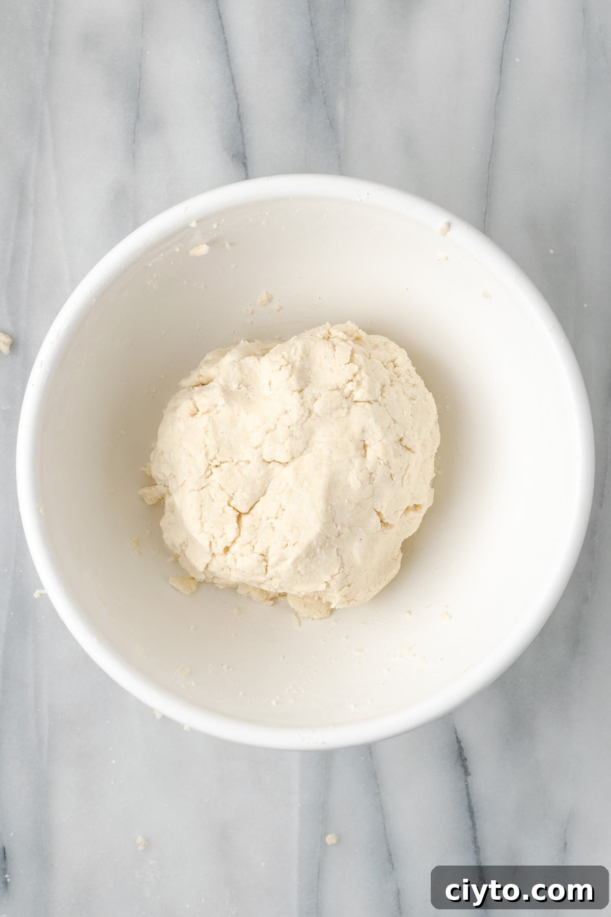 How to Make a Flaky Gluten-Free Pie Crust 12 Gluten free pie dough formed into a large ball in a white mixing bowl.