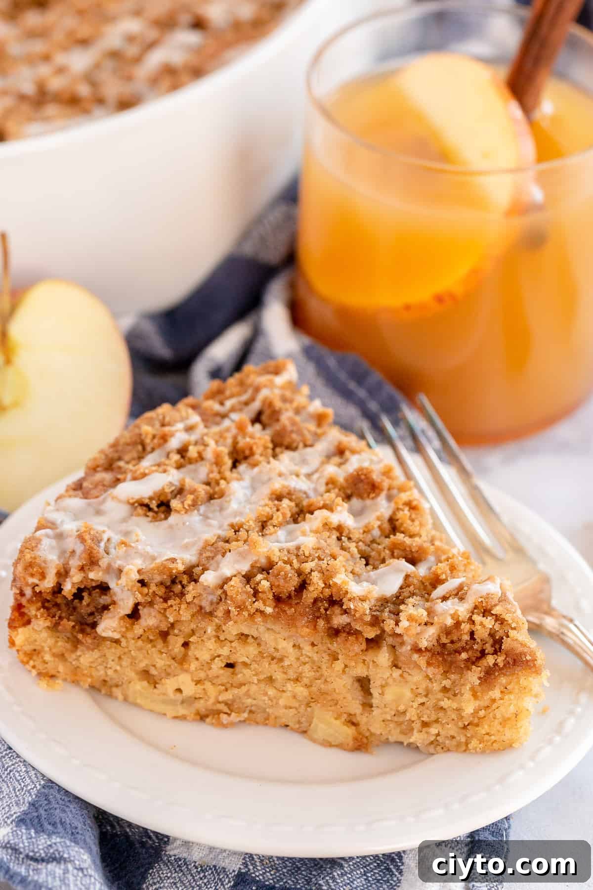A sliced of glazed apple coffee cake on a white plate.