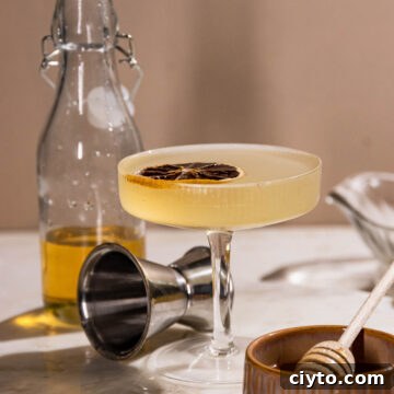 Side shot of a coupe glass filled with a vibrant bee's knees cocktail.