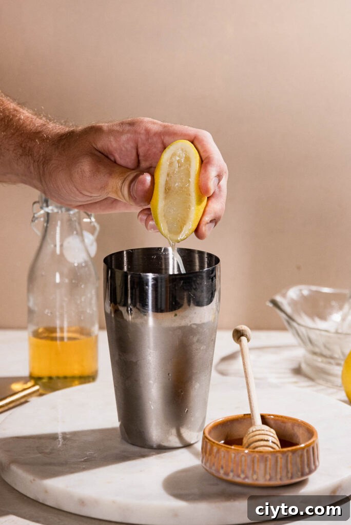Classic Bee's Knees Cocktail Recipe 6 Lemon being squeezed into cocktail shaker.