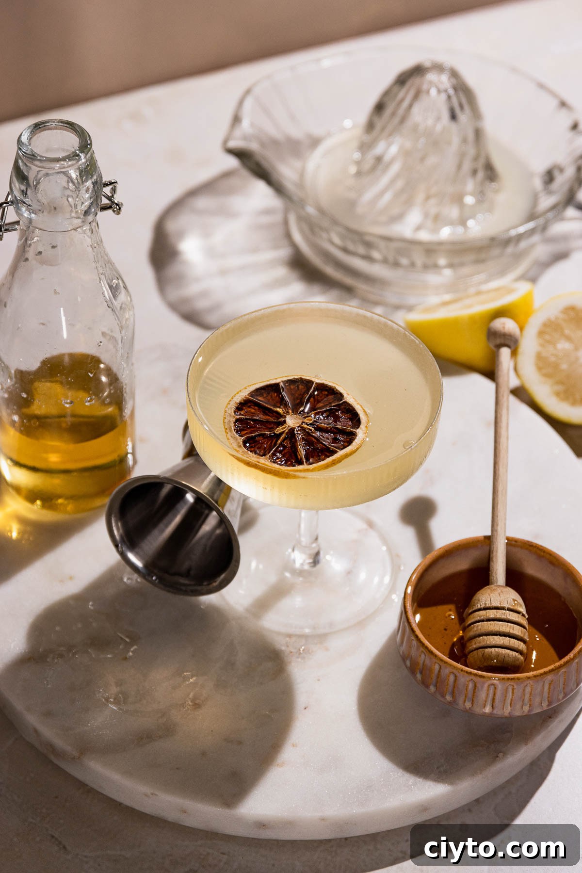 Classic Bee's Knees Cocktail Recipe 9 Table with coupe glass of gin and lemon bee's knees cocktail.