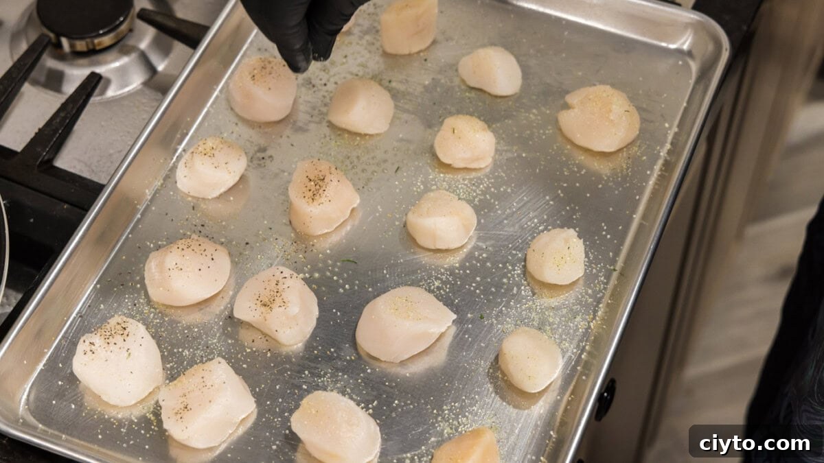 Garlic Butter Baked Scallops Recipe 6 hand sprinkling garlic salt and pepper on scallops