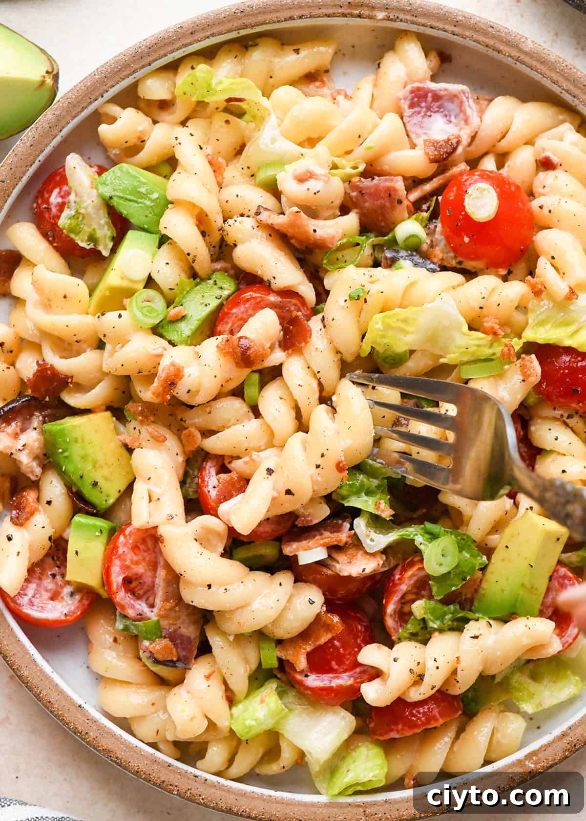 BLT Pasta Salad Recipe with Bacon, Tomato and Lettuce 5 a fork taking a bite of BLT Pasta Salad on a plate