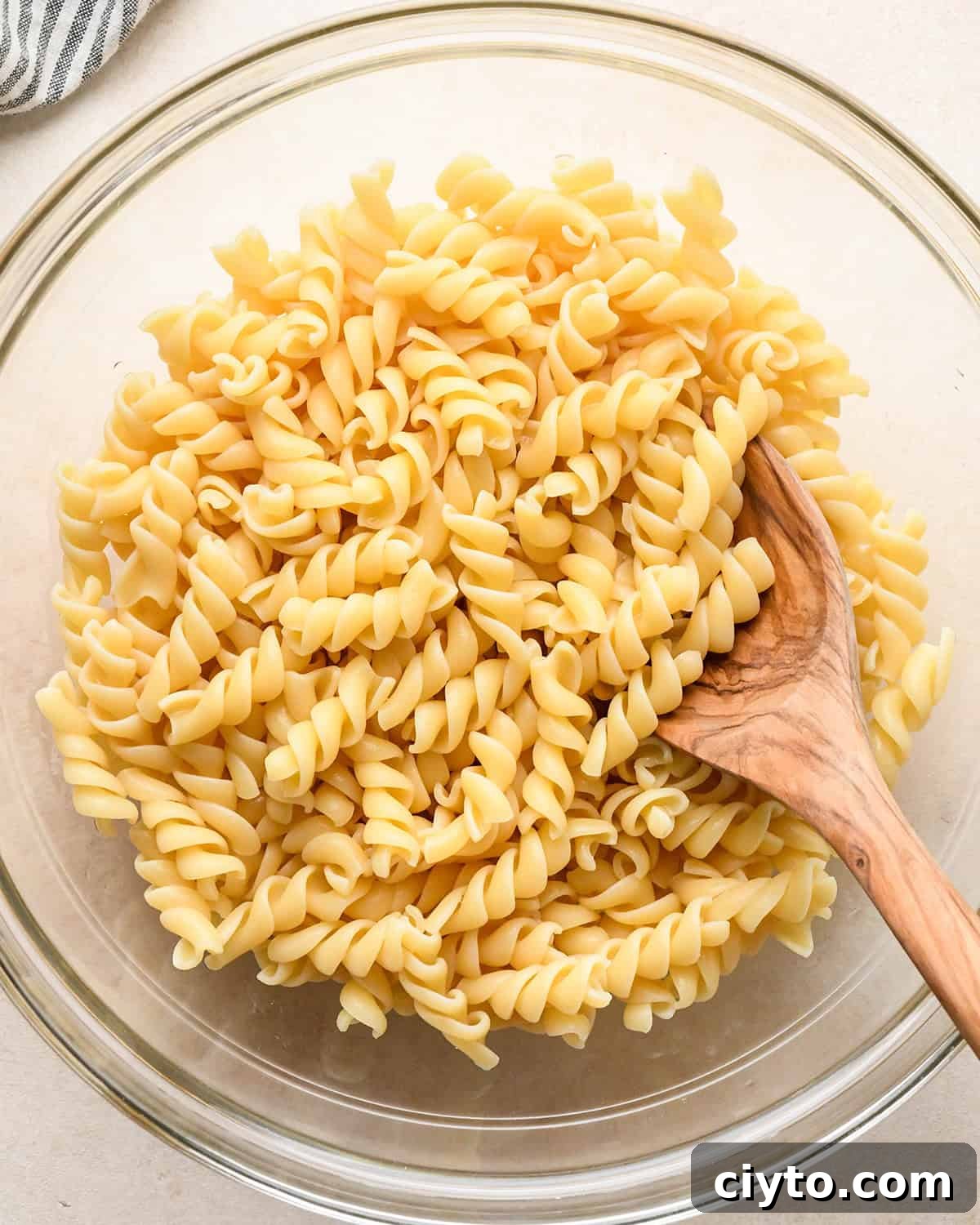 BLT Pasta Salad Recipe with Bacon, Tomato and Lettuce 8 rotini pasta in a glass bowl with a wooden spoon