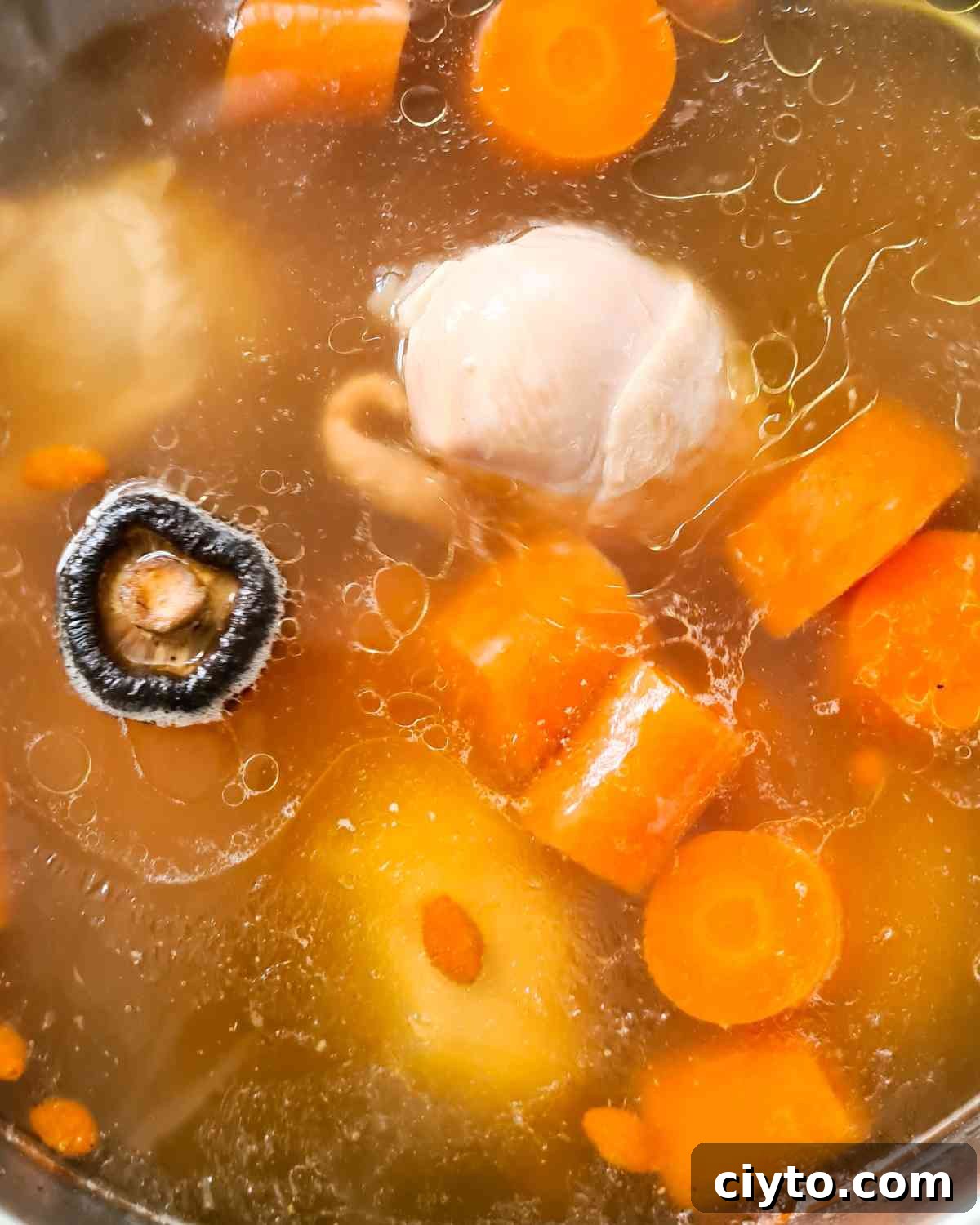 Close up of a pot of clear chicken soup