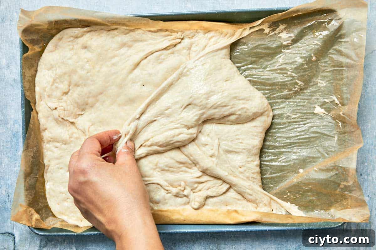 Dough being gently folded from the sides after rising.