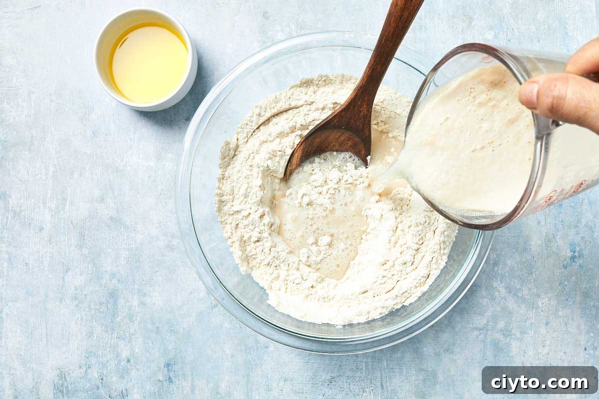 Yeast mixture being poured into flour to form dough.