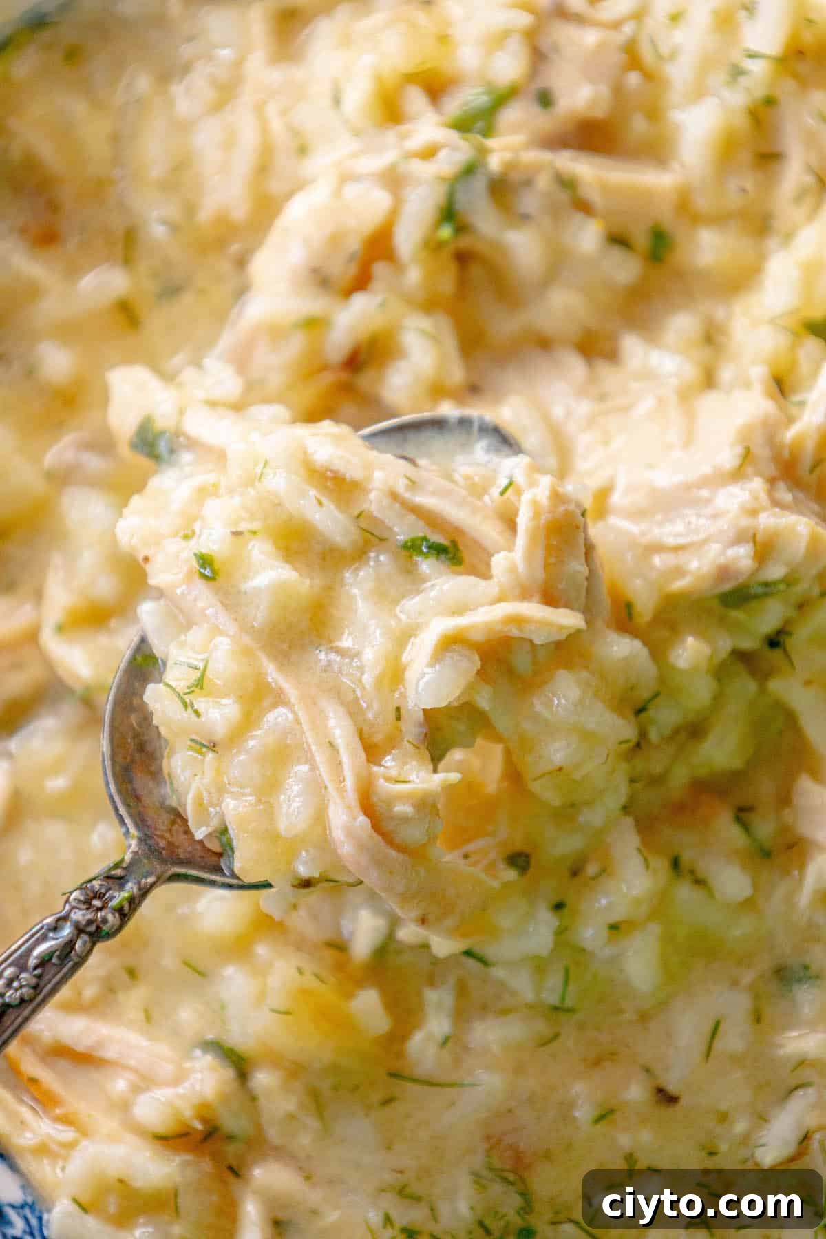 Authentic Greek Avgolemono Soup Recipe 5 Avgolemono soup in a blue bowl with a spoon.